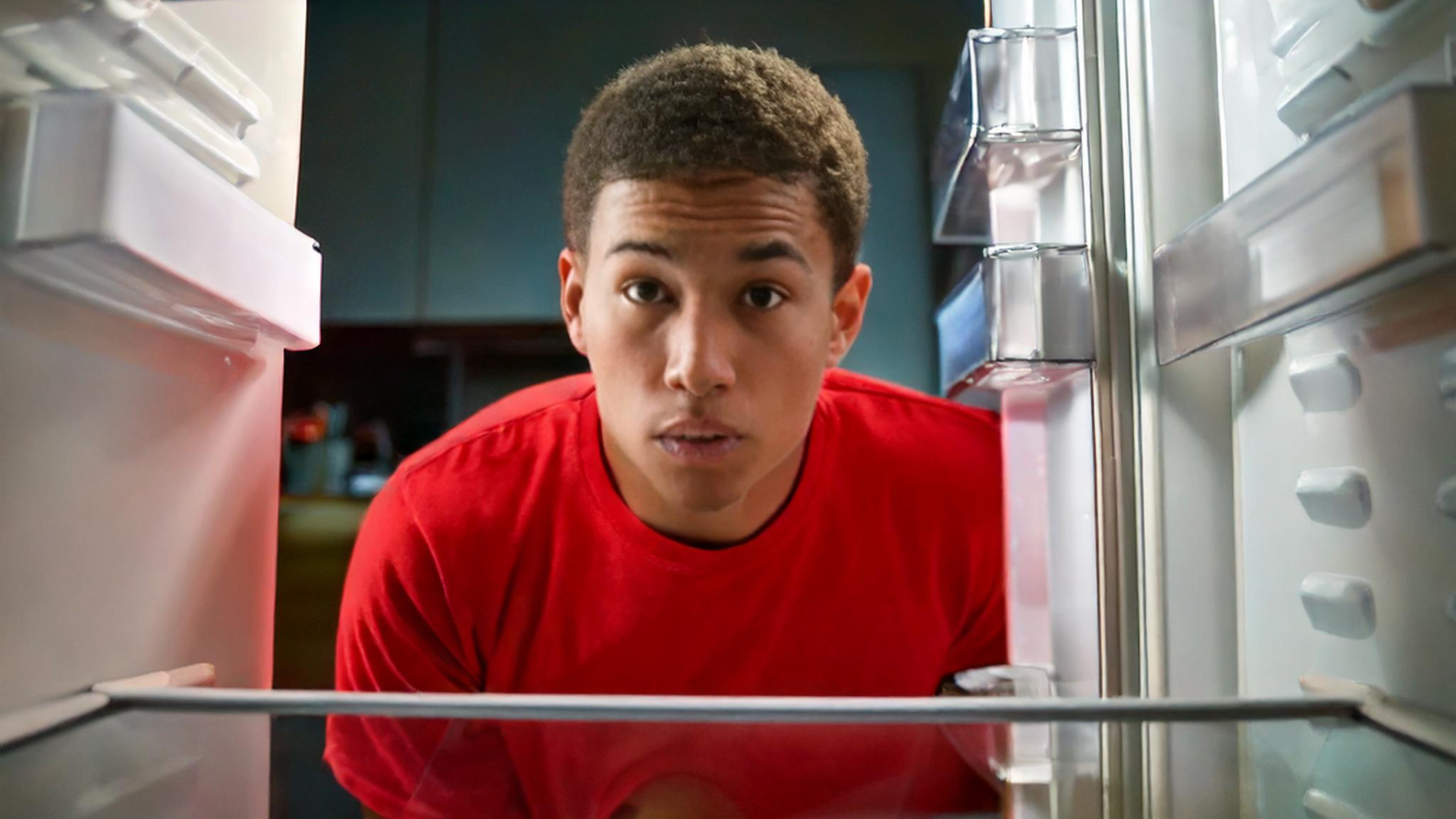 young man looking into an empty refrigerator