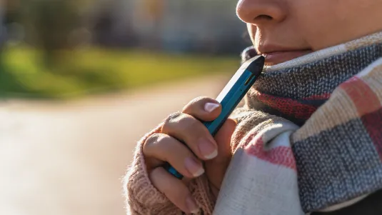 Young girl holds in hand new Vape Pod System, electronic cigarette, vaping concept.