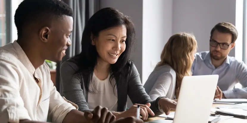 woman and man looking at something on the computer screen with two people behind them