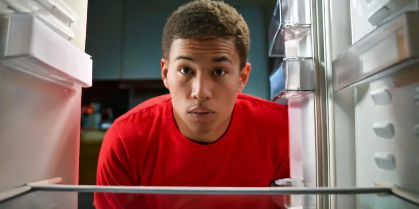 young man looking into an empty refrigerator