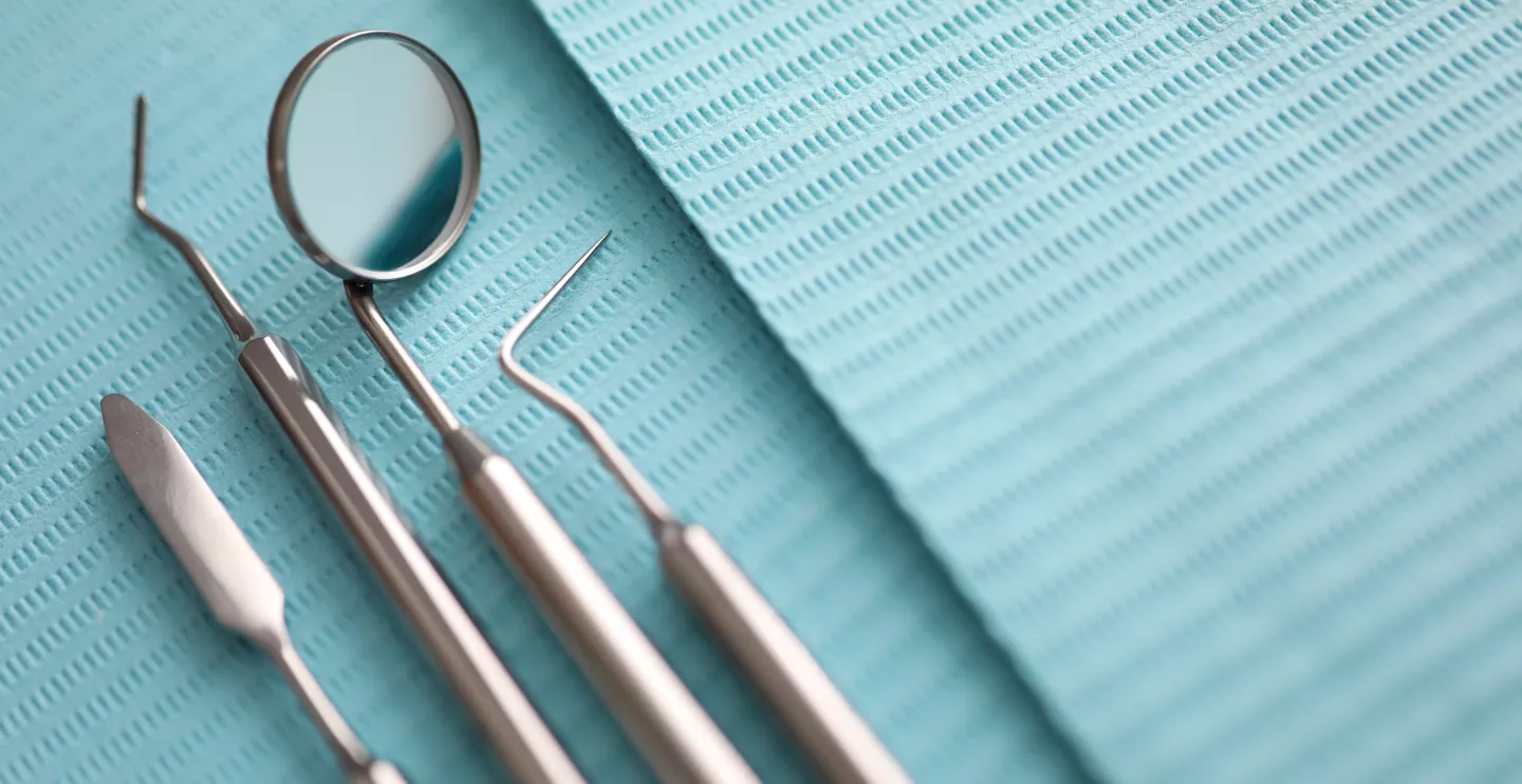 Pile of dentist tools lying at green tissue ready to be used close-up