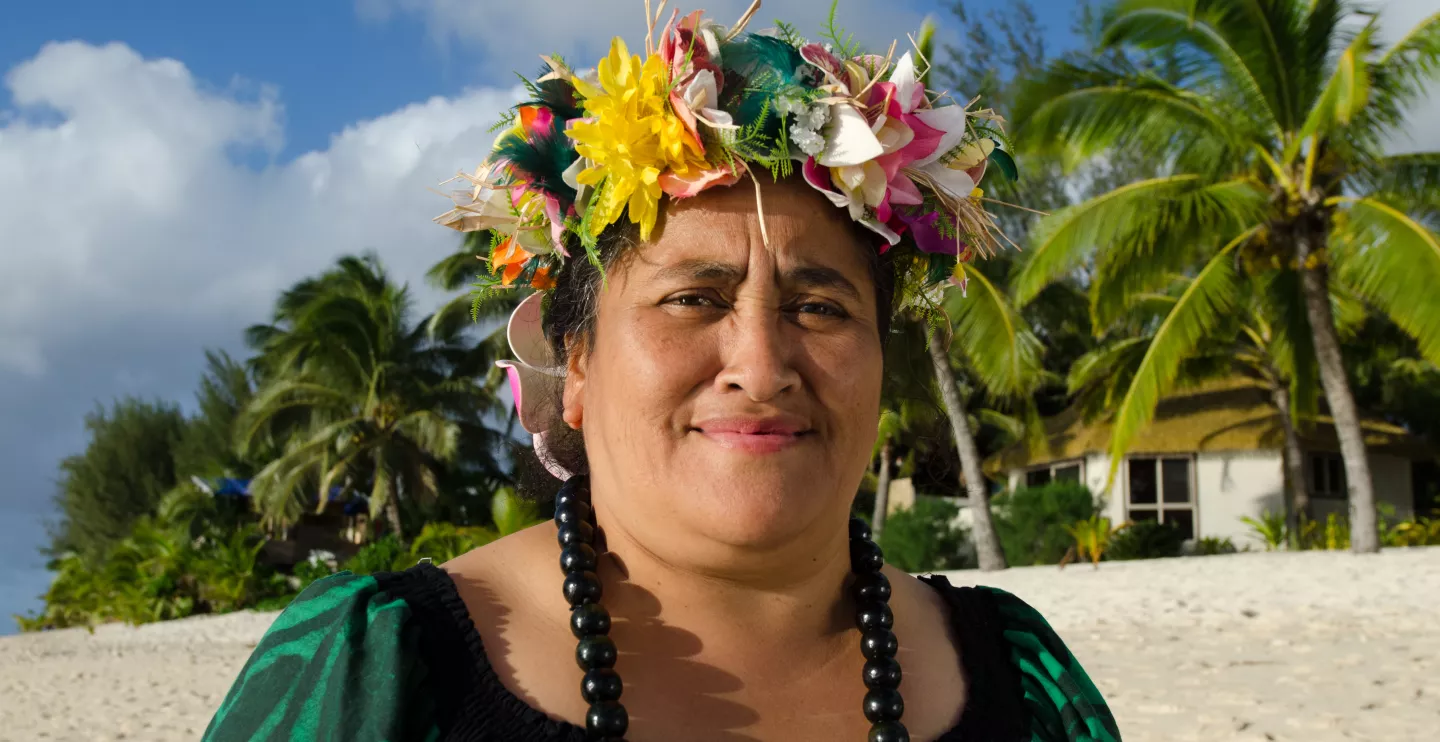 Portrait of active senior Polynesian Pacific Islander woman looking at the camera standing on tropical island beach with palm trees in the background in Rarotonga, Cook Islands