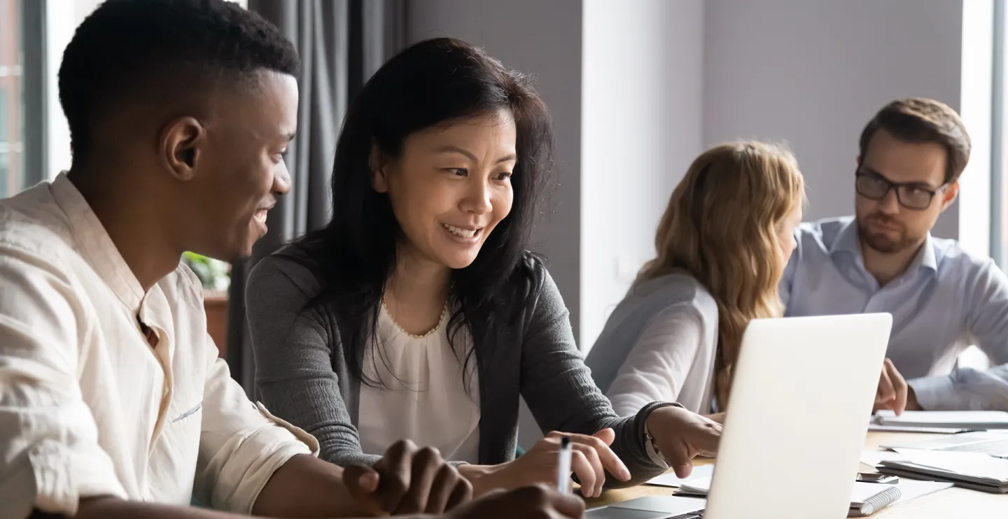 woman and man looking at something on the computer screen with two people behind them