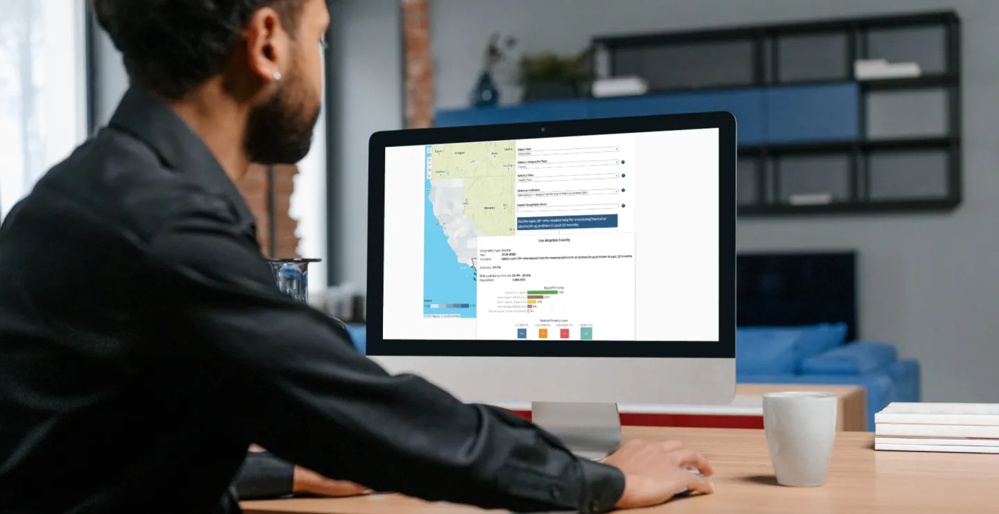 man at a computer looking at AskCHIS Neighborhood Edition with a map of California and bar charts