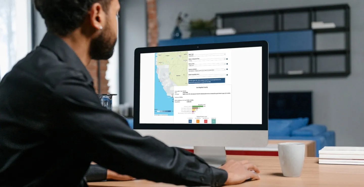 Man looking at a computer monitor with a map of California on the screen along with a graph.