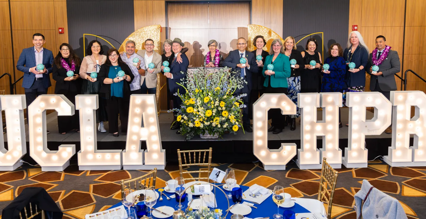 group of people on a stage standing in front of UCLA CHPR marquee lights