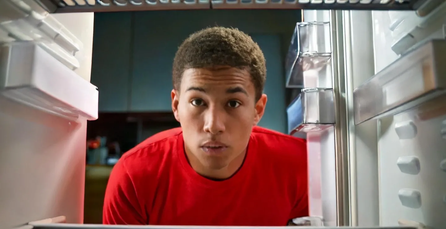 A young Black adult looks into an empty refrigerator