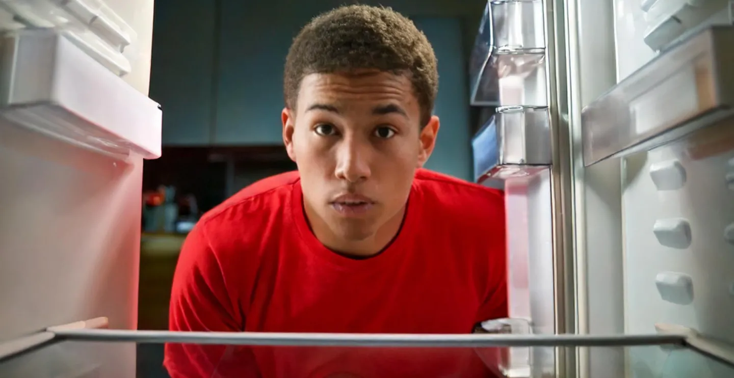 young man looking into an empty refrigerator