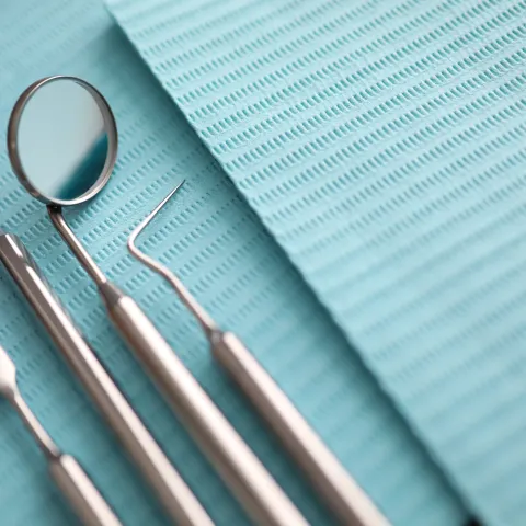 Pile of dentist tools lying at green tissue ready to be used close-up