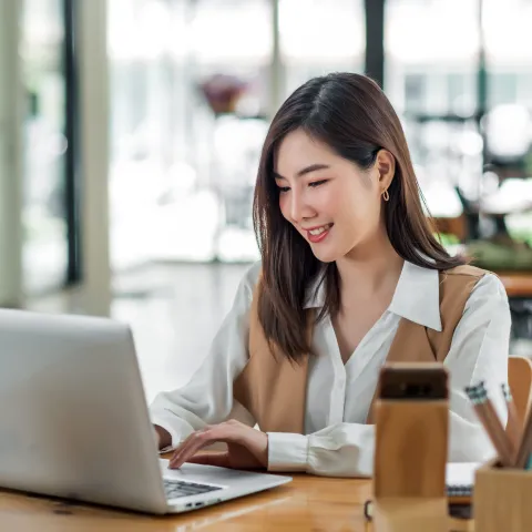 Happy young businesswoman sitting at table in cafe with tab top computer.