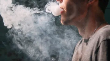 Photo of man exhaling e-cigarette vapor