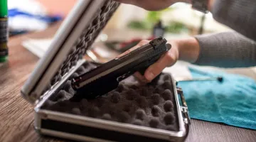 hand putting a gun into a case