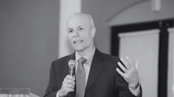 black and white photo of rick brown speaking into a microphone