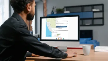 Man looking at a computer monitor with a map of California on the screen along with a graph.