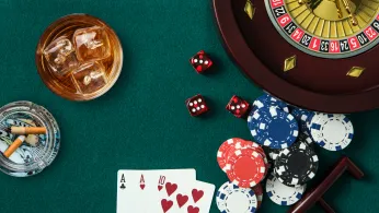 Overhead shot of playing cards, dice, casino chips and a roulette wheel